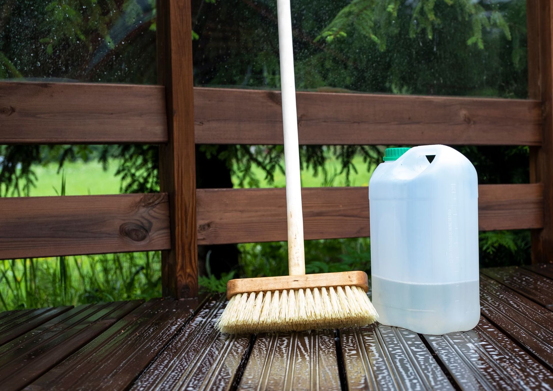 Timber deck being scrubbed with a cleaning brush and deck cleaning solution